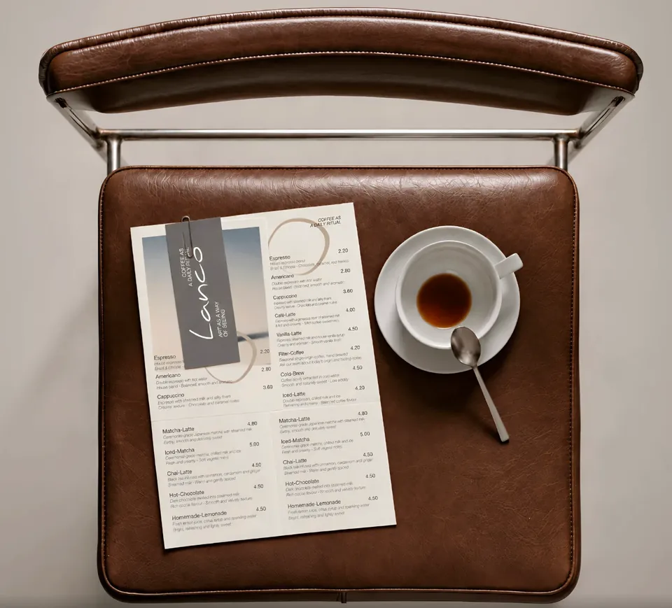 Vue de dessus d'une chaise en cuir : un menu de café et une tasse d'expresso posés sur l'assise. Image générée par IA.